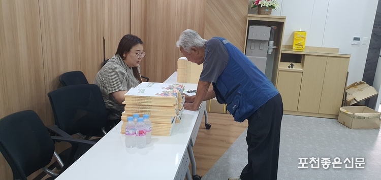 교육에 참석한 조합원이 관인농협에서 발간한 교제를 받고 서명하고 있다.